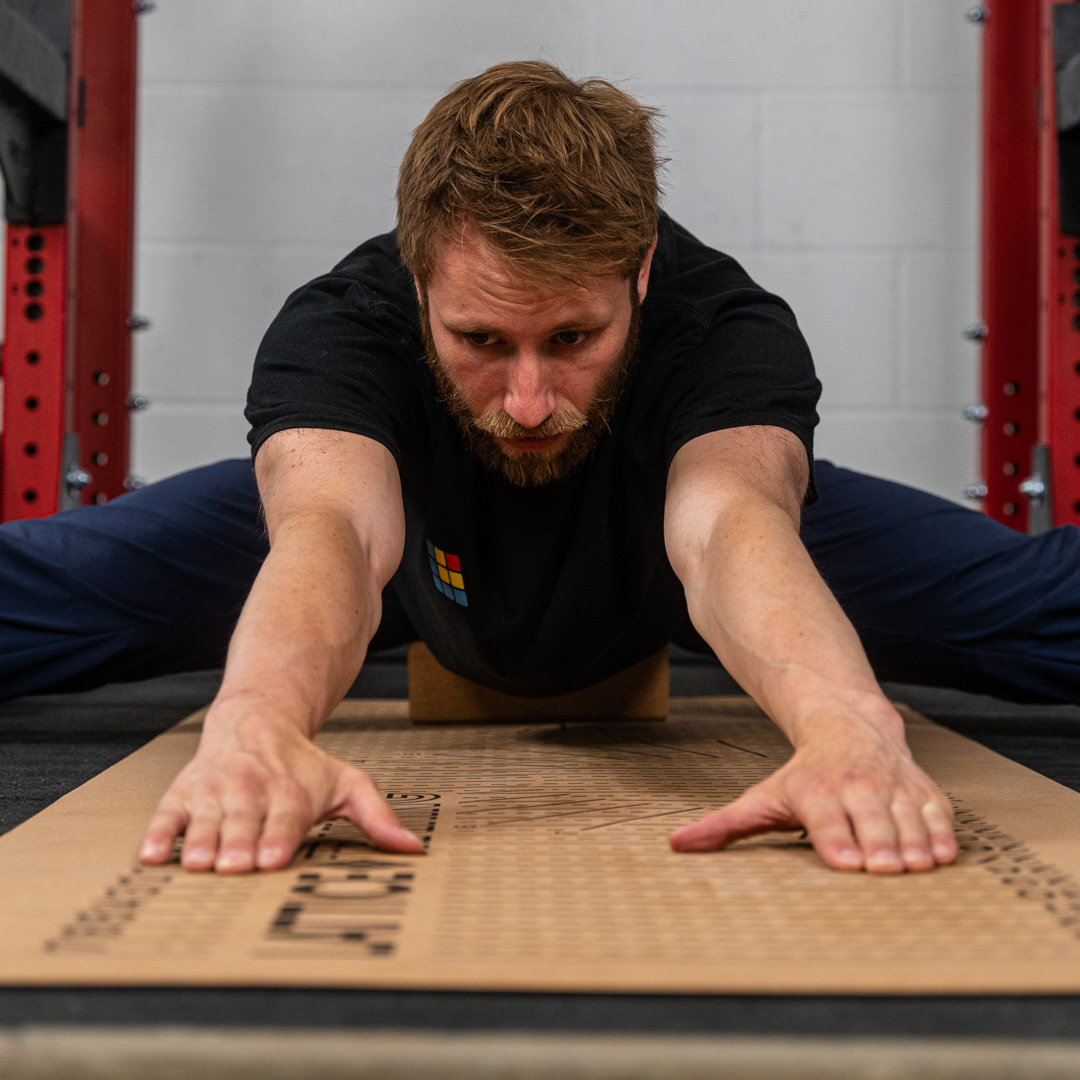 Lattice Coach Josh Hadley performing a pancake stretch with a flex block on a flex mat